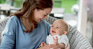 Mum and baby laughing while cuddling on a chair