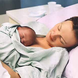 A mum laying next to her newborn baby