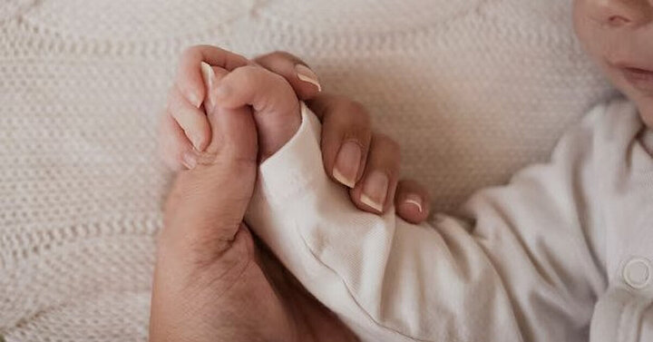 baby holding mum's finger