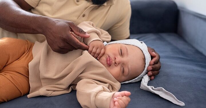 Baby sleeping next to dad