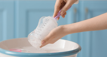 Washing up a baby bottle in sink