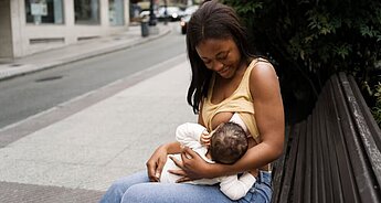 Mum breastfeeding baby on a bench