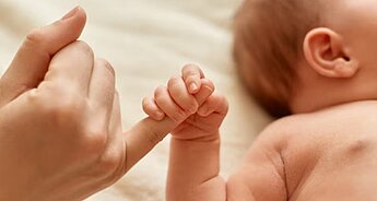 Newborn holding mother's finger