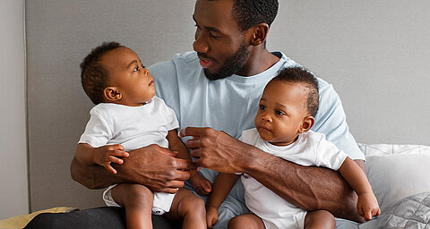 Man holding two babies