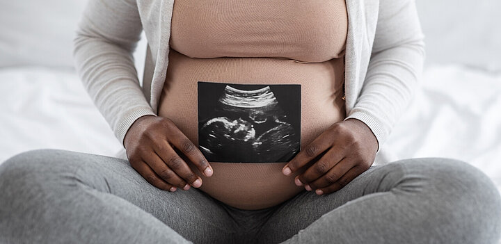 Pregnant woman holding ultrasound scan near her stomach