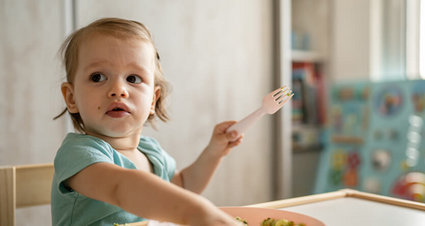 Toddler spoon feeding herself