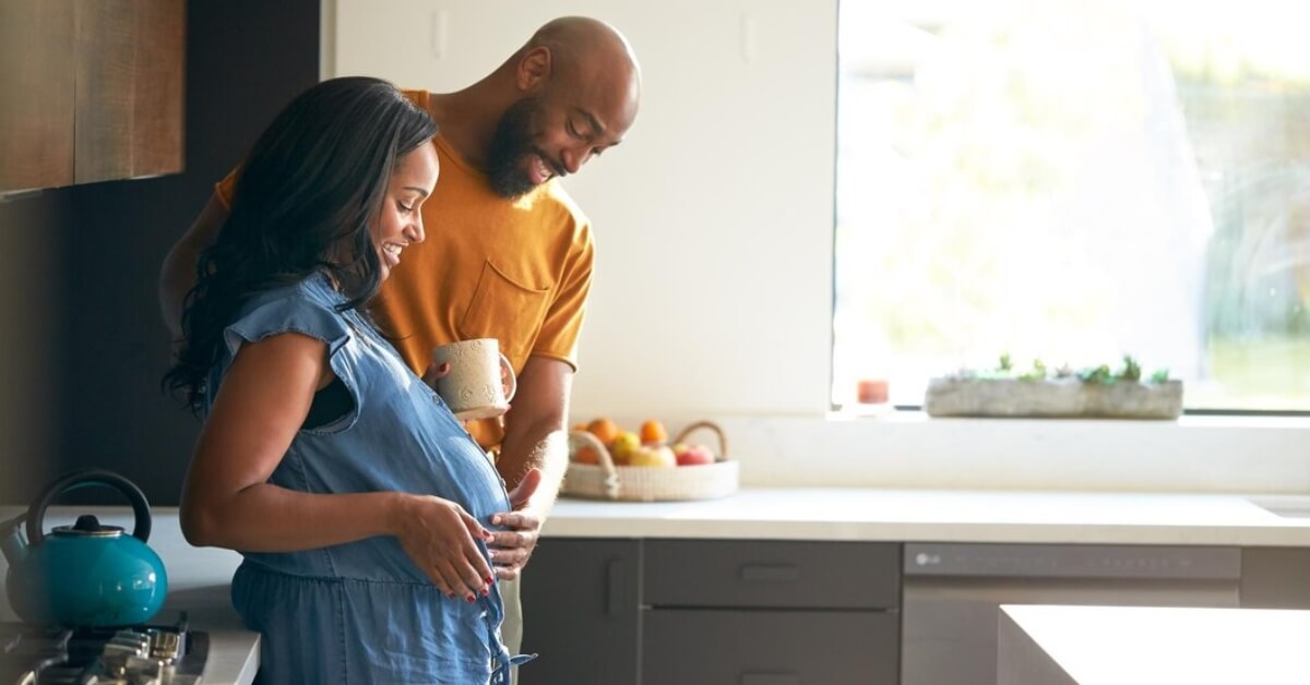 Couple in the kitchen admiring baby bump