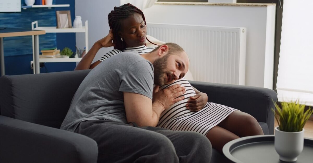 Dad pressing ear to pregnant partners belly