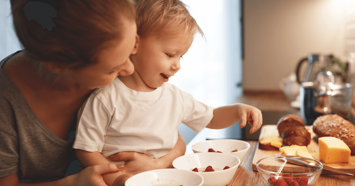 Mum and baby making up porridge topped with raspberries