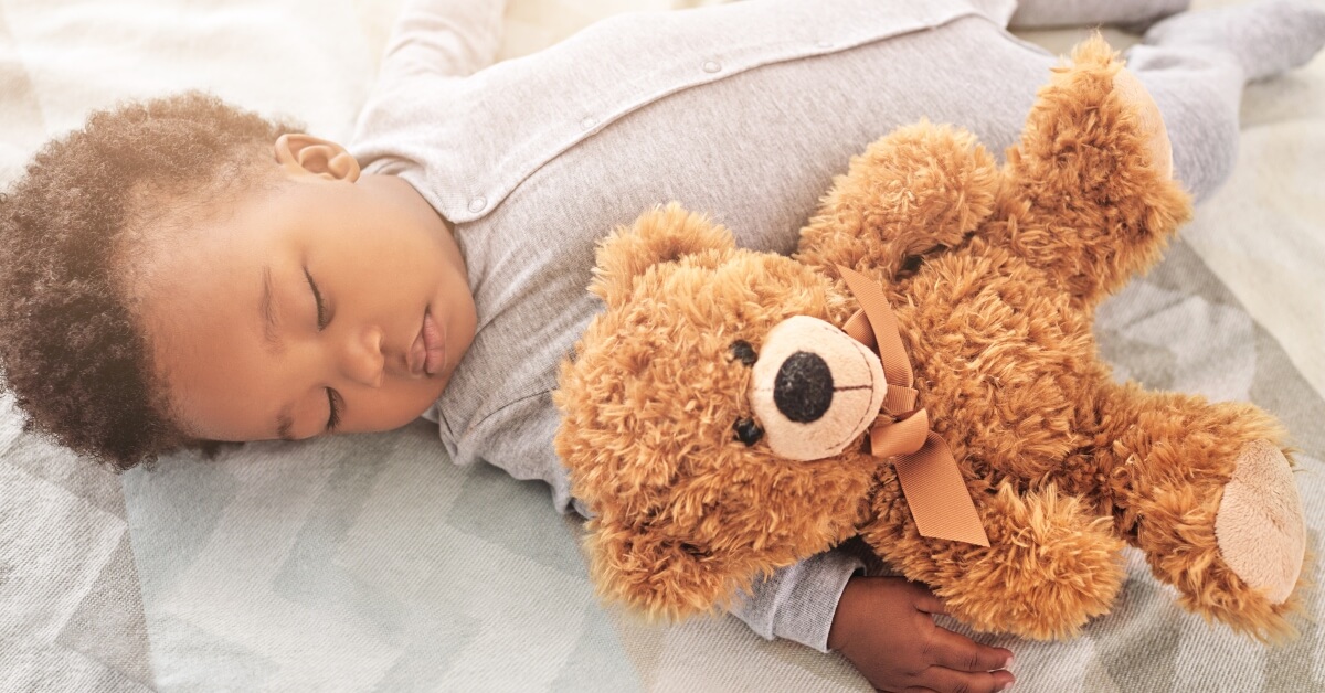 Baby napping in bed with teddy bear