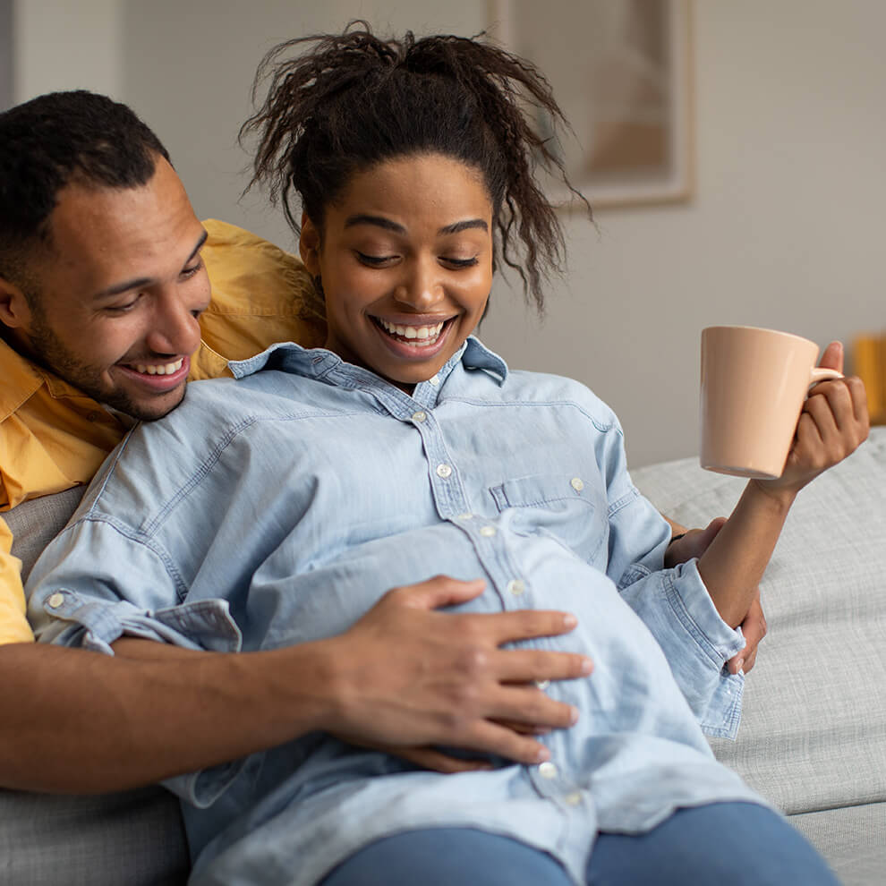 Couple sitting together with holding a baby bump