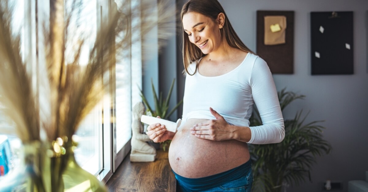 Pregnant mum massaging lotion into bump